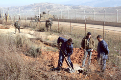 عمال يصلحون القسطل وبدا جنود دوليون واسرائيليون على جانبي الحدود
