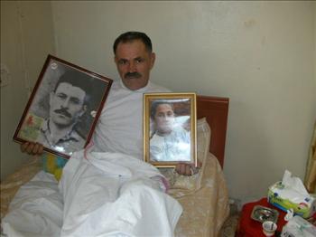 شبلي يحمل صورتي والده وولده الشهيدين (طارق ابو حمدان)