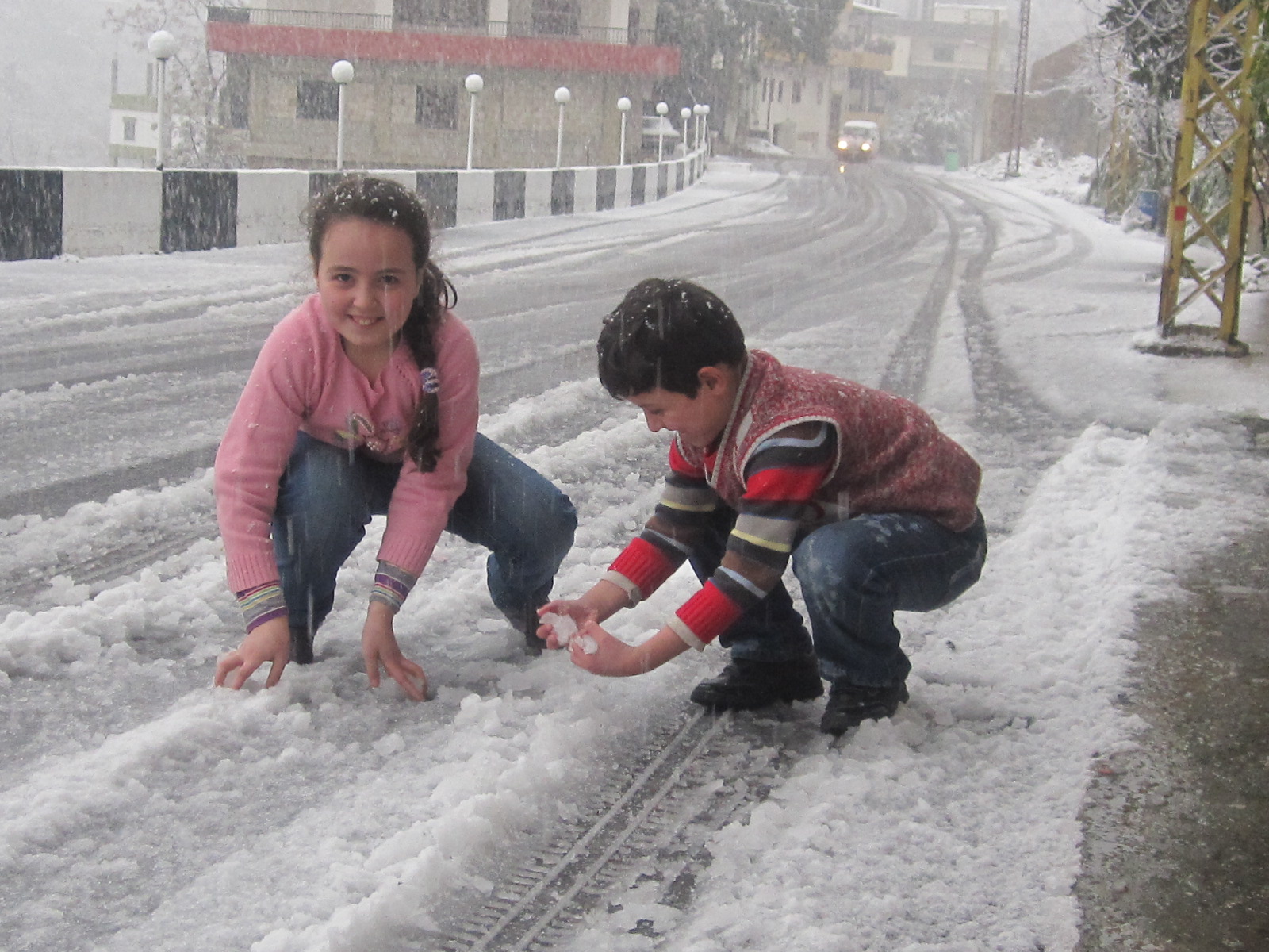 أطفال يلهون بالثلج المتساقط