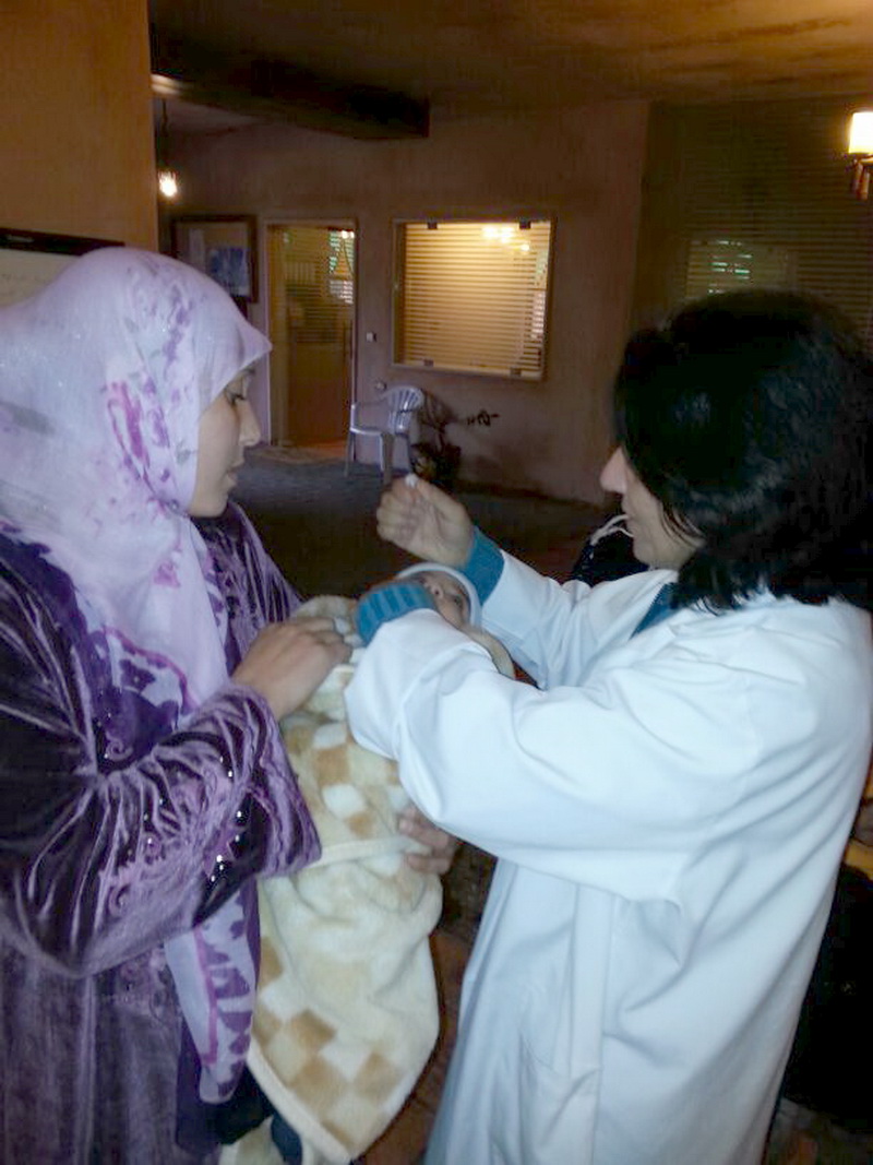 الممرضة سميرة من جمعية نور تعطي جرعة بالفم لاحد الاطفال في السوريين