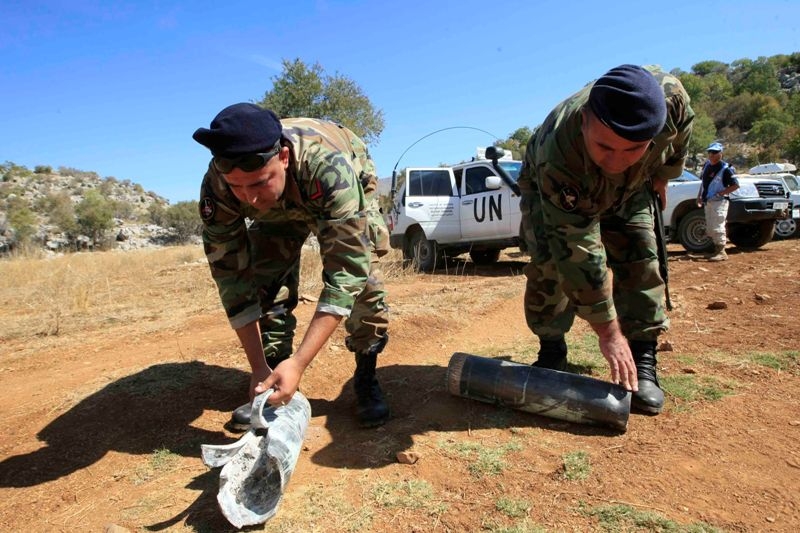  عنصران من الجيش يحملان قنبلتين من مخلفات القصف الاسرائيلي