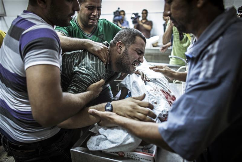 والد طفل من عائلة شحيبر ينتحب فوق جثمان طفله الذي استشهد مع طفلين اخرين من العائلة في غارة اسرائيلية على غزة امس (ا ب ا)