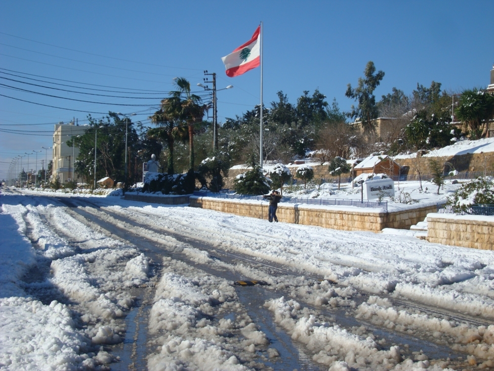 علم لبنان يرفرف وشخصان يلتقطان سلفي للثلج