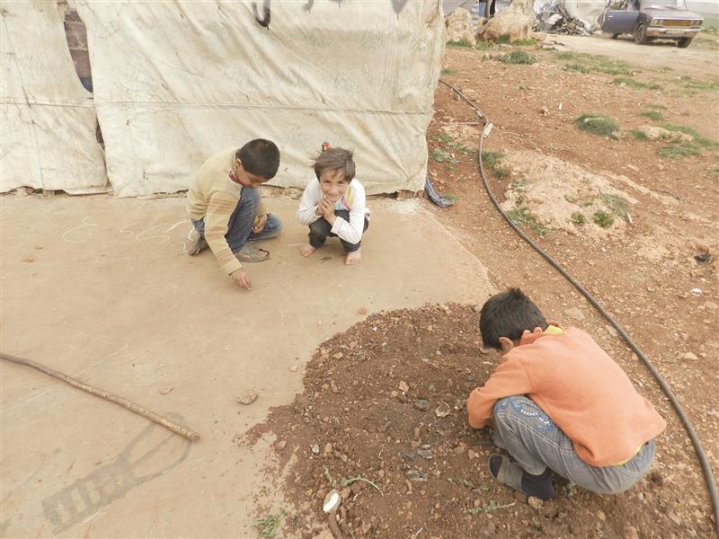 أطفال نازحون يلهون بالتراب بينما مخاطر الأمراض بسبب التلوث تلاحقهم يومياً (طارق أبو حمدان)