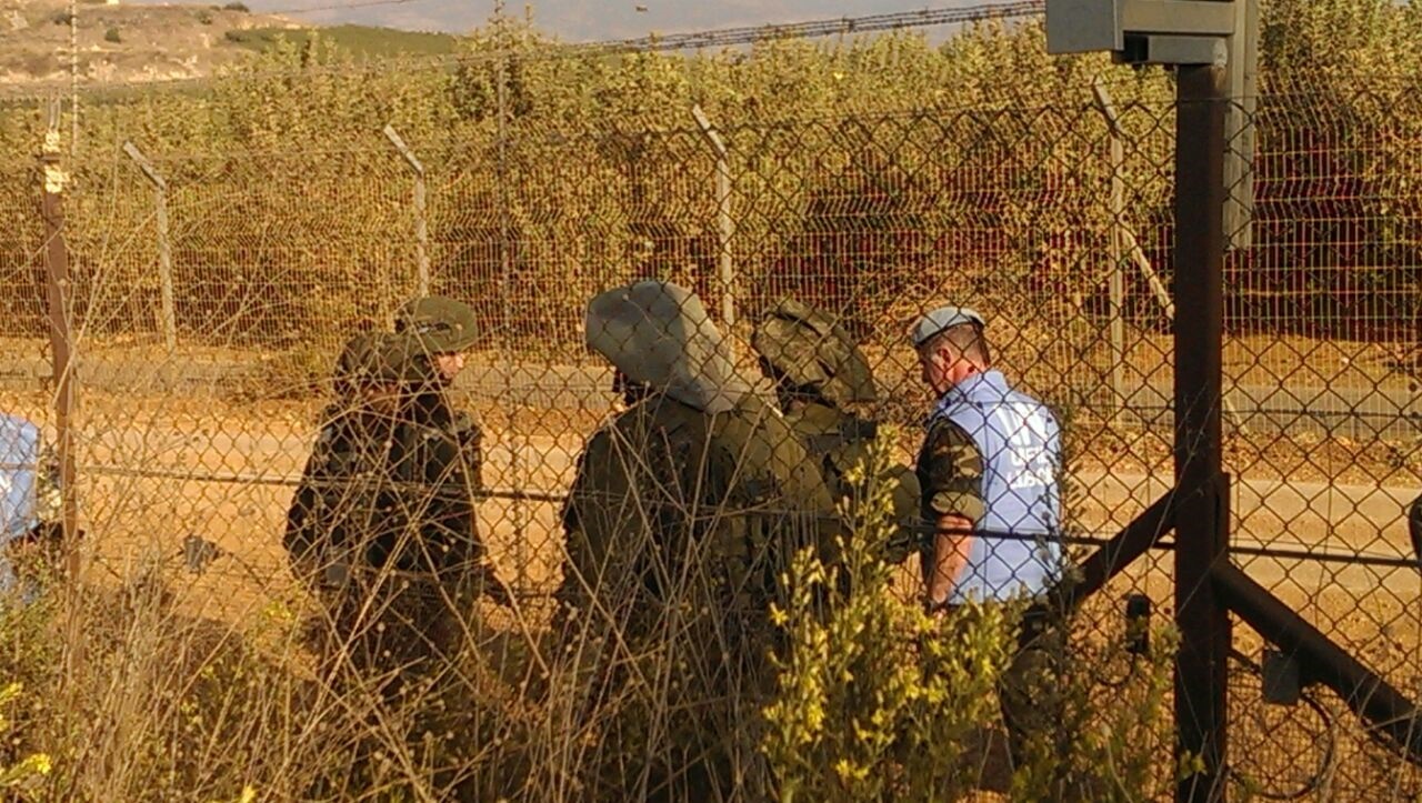 فريق مراقبي الهدنة اثناء إجراء التحقيق والى جانبهم جنود العدو