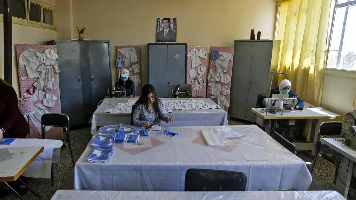 مدرّسات يعملن على خياطة وتجهيز كمامات داخل معهد مهني في دمشق