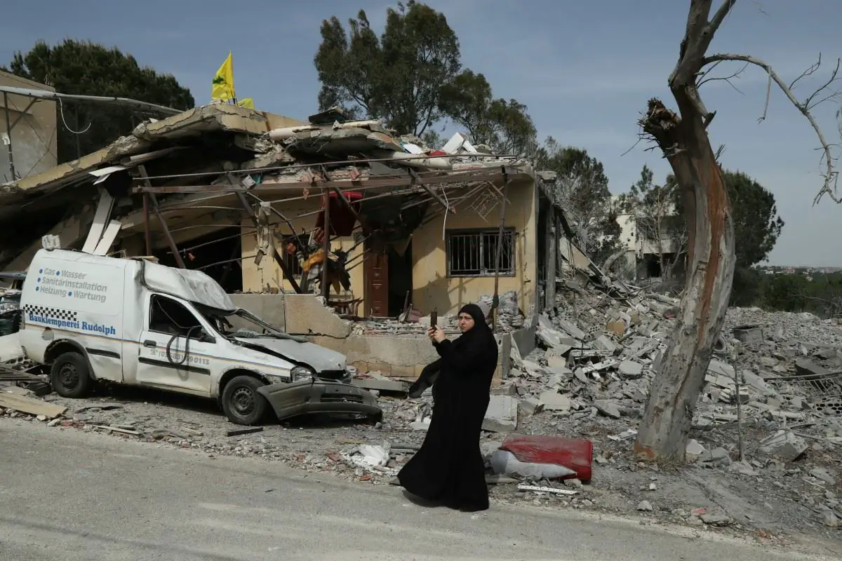 امرأة تقف أمام منزل دمّرته غارة إسرائيلية في بلدة حانين (أ ف ب).