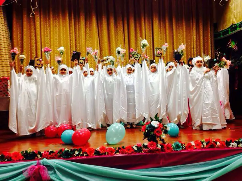 اليافعات  يرفعن كتاب القرآن الكريم في أثناء الحفل احتفاءً باليوم المميز 