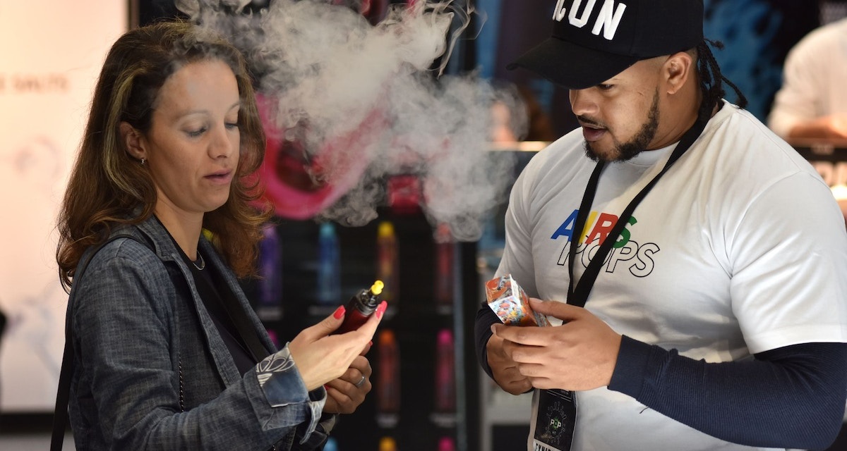 سيدة تدخن السجائر الإلكترونية خلال معرض لبيعها بمدينة برمنجهام في بريطانيا