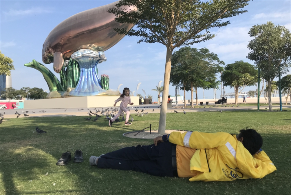 (عامل نظافة آسيوي يستريح في أحد الحدائق العامة على كورنيش الدوحة (الأخبار)