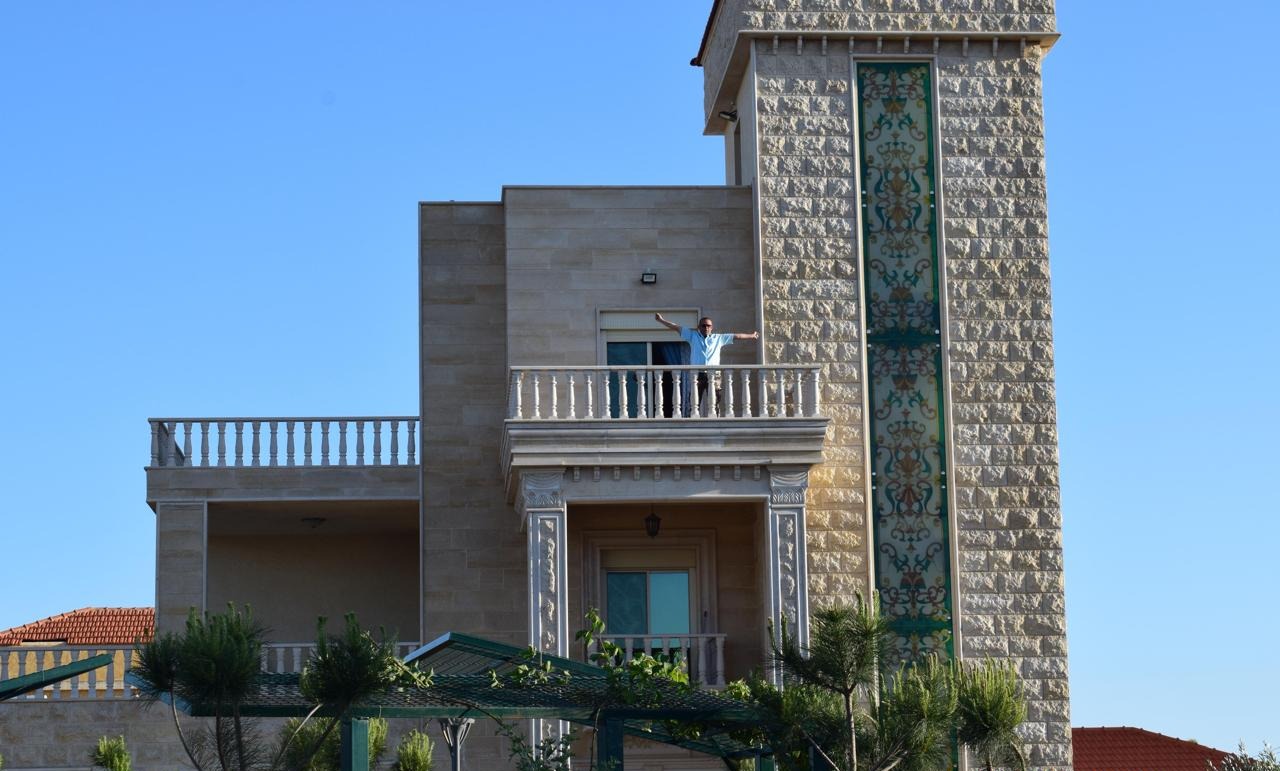 يطل حسن السيد علي، من شرفة منزله في الخيام الذي بناه لعائلته بمدخرات عمره.. قصفته إسرائيل خلال حرب 2024، وهو لا يعلم ما تبقى منه اليوم