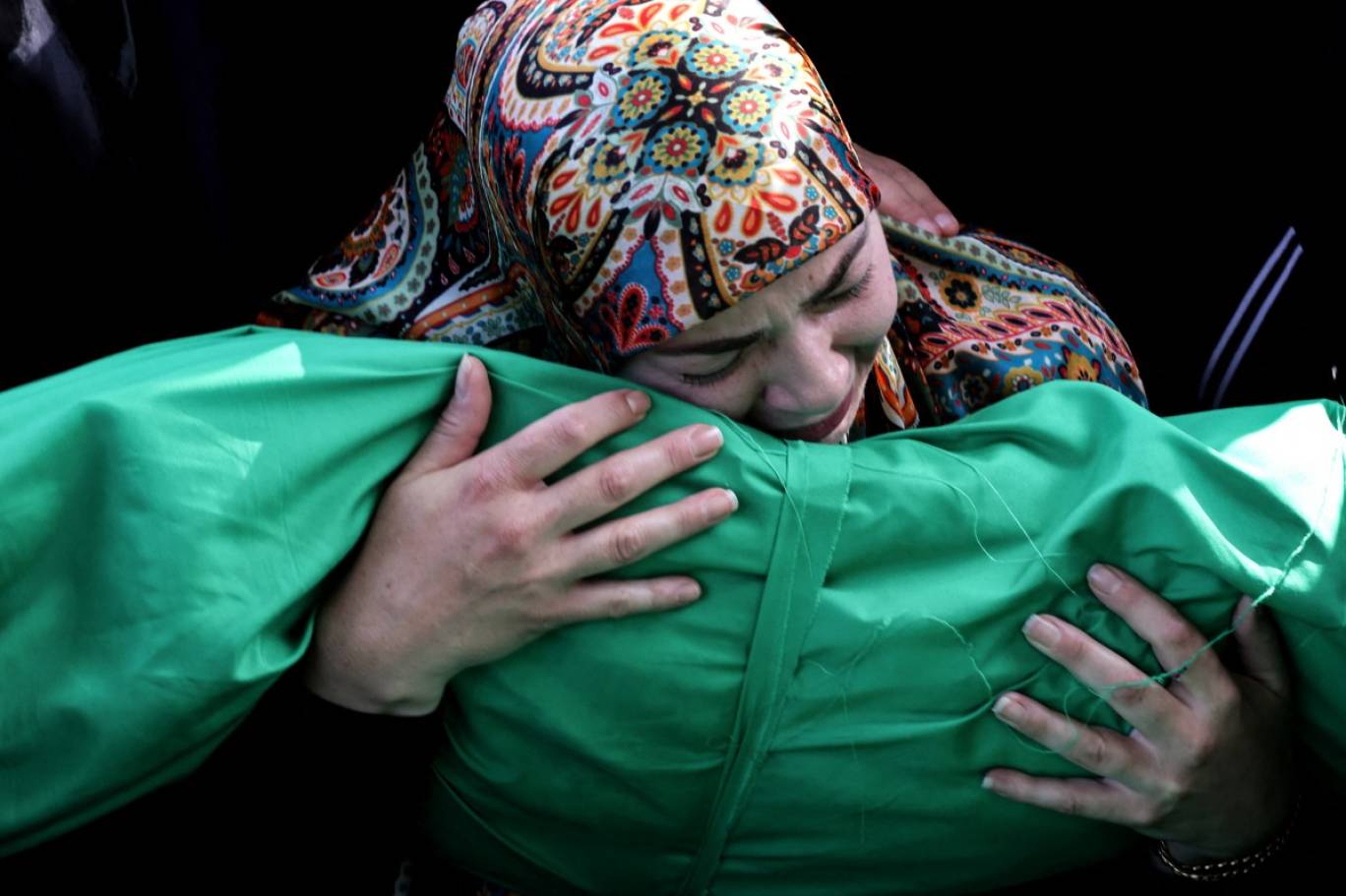 أم تحمل جثة طفلها الذي توفي بسبب القصف الإسرائيلي في 10 مايو الحالي (أ ف ب)