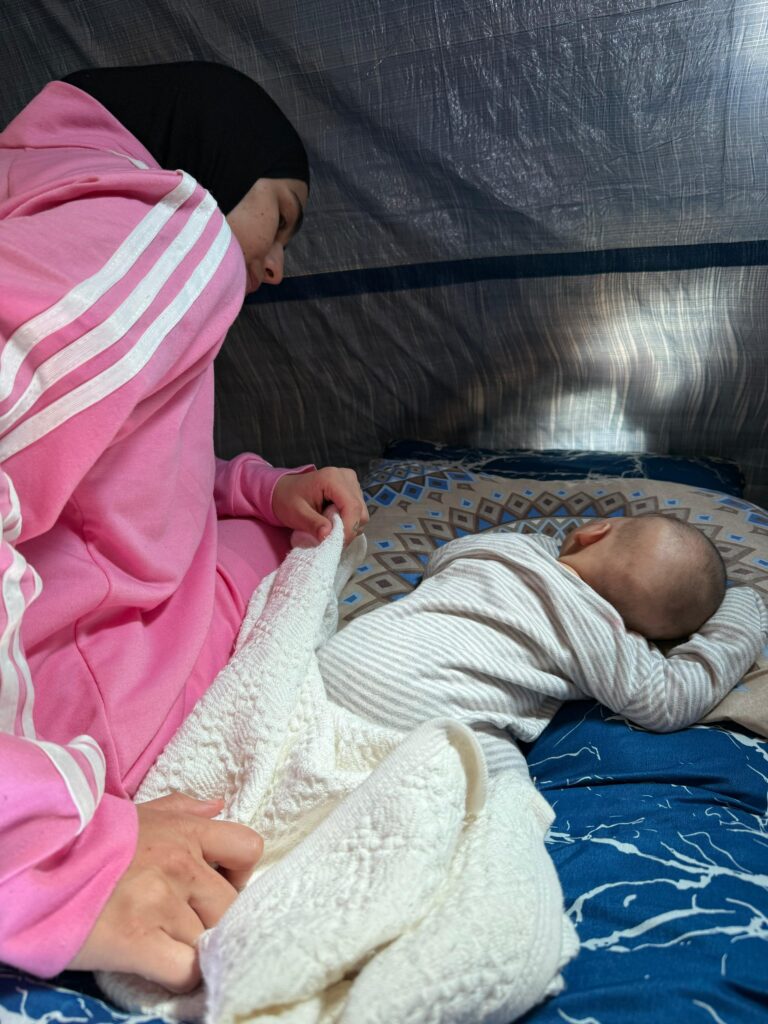 هناء مع مولودها في خيمة النزوح في إحدى مدارس صور